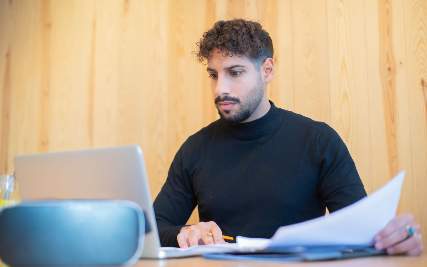 Self-employed professional reviewing paperwork at his laptop